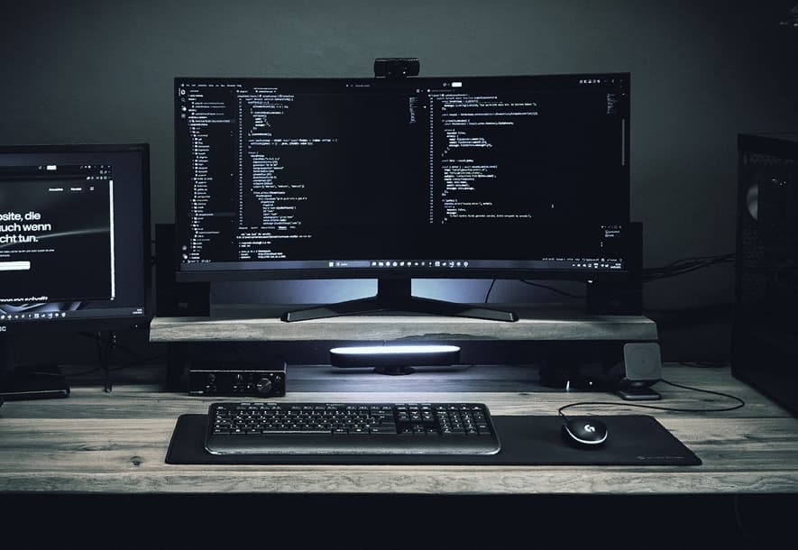 Entwickler-Arbeitsplatz mit zwei Bildschirmen und Quellcode